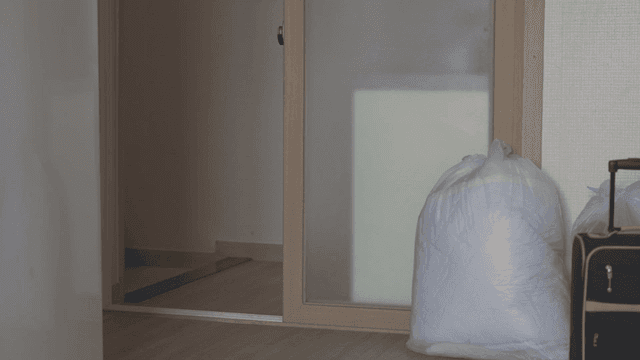 상자를 들고 빈집을 나서는 여성