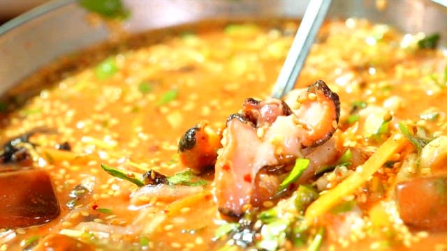 물회 안에 있는 신선한 뿔소라를 숟가락으로 집어올리는 장면