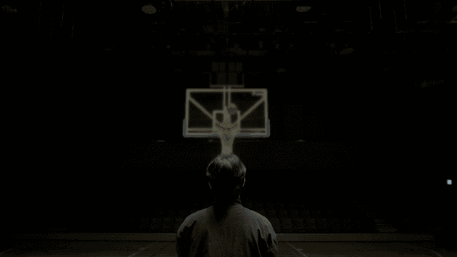 Back view of man throwing ball on indoor basketball court