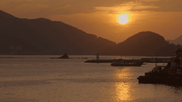 Sunset over a calm sea with a lighthouse