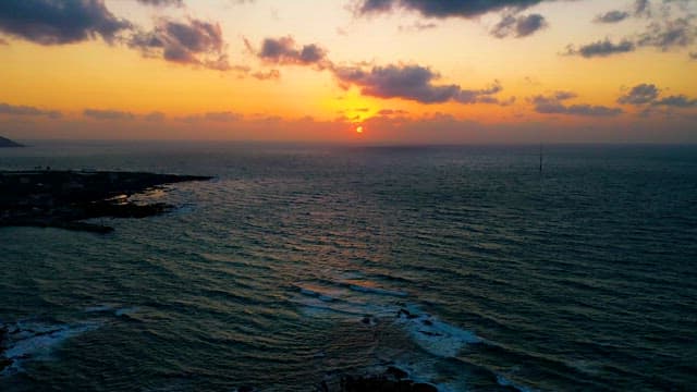 잔잔히 흘러가는 바다의 수평선 너머 일몰