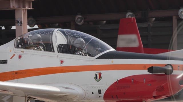 Military aircraft with pilots on board taxiing near the hangar