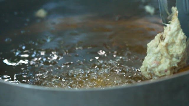 Frying the battered chicken in hot oil in a pan