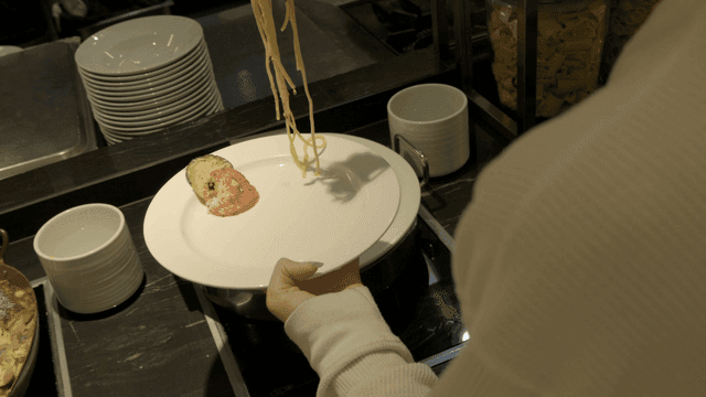 Person putting pasta on buffet plate