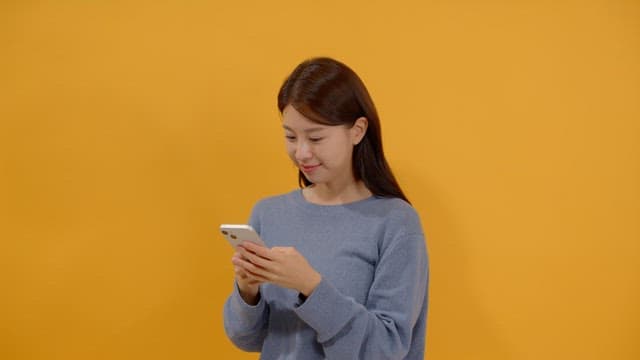 핸드폰으로 메시지를 주고 받으며 웃는 긴 머리 여성