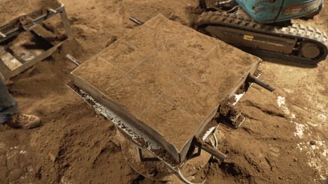 Workers handling a soil block in a factory