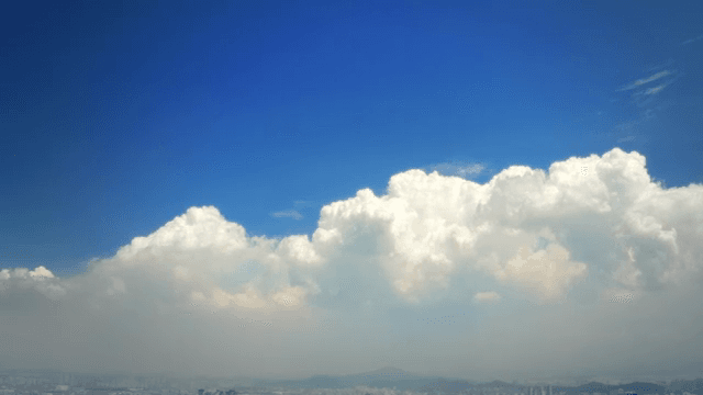 Clear sky with fluffy clouds over a city