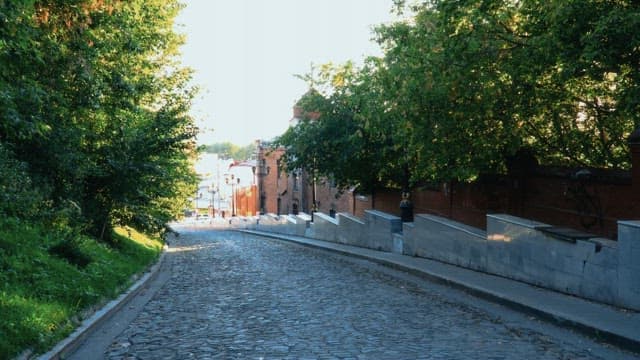 Downhill view of an urban alley with trees and buildings