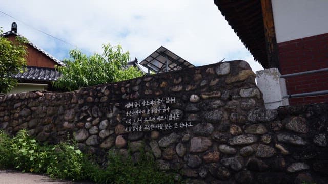 Traditional stone wall with a house and greenery