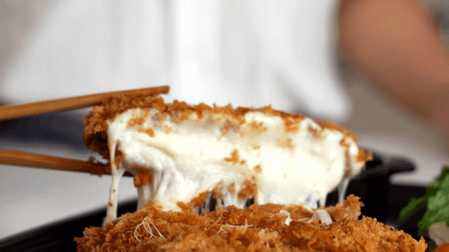 젓가락으로 들어 올린 치즈 돈가스