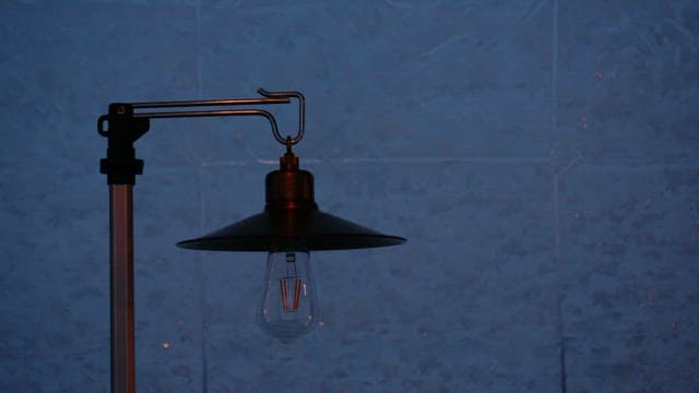 Hand Turning on an Electric Lamp in a Dark Room