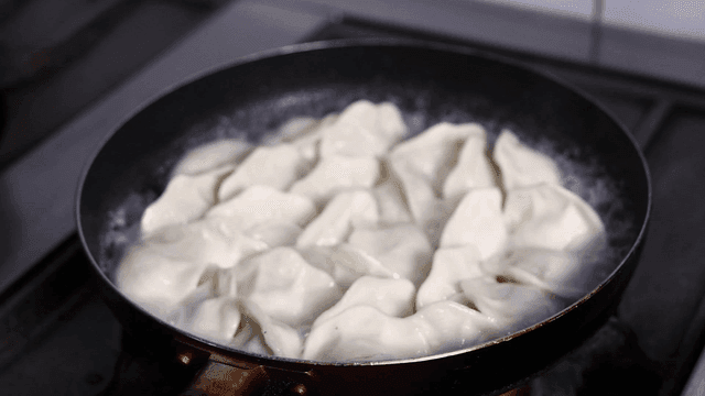 Dumplings boiling in a pot with steam