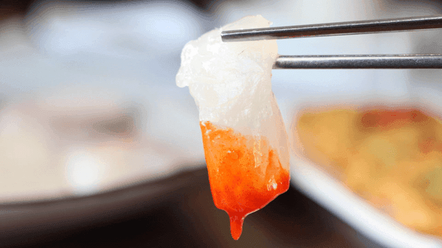 Piece of sea bass sashimi dipped in red sauce