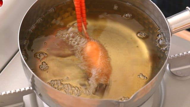 Frying a hot dog in hot oil with red chopsticks