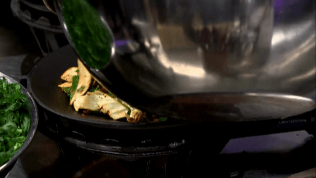 Placing various seasoned vegetables into a wok