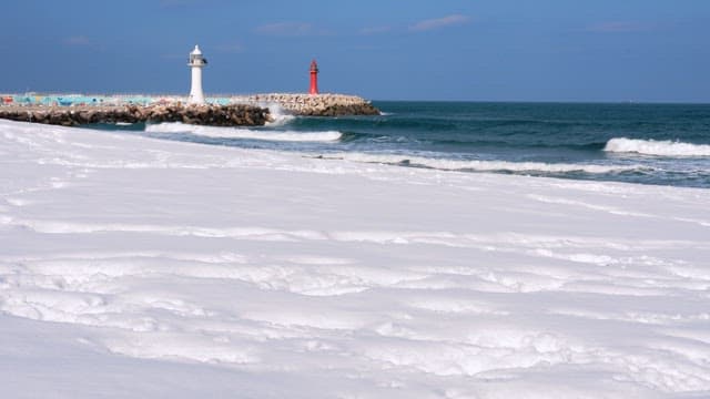 Sunny winter day in a snowy beach with two lighthouses