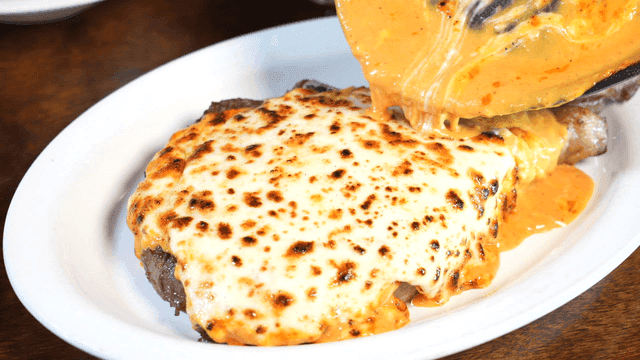 Cheese sauce poured over grilled steak