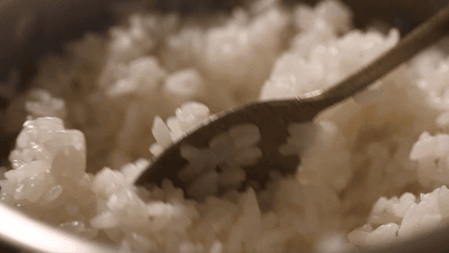 Steamed rice stirred with spoon in pot