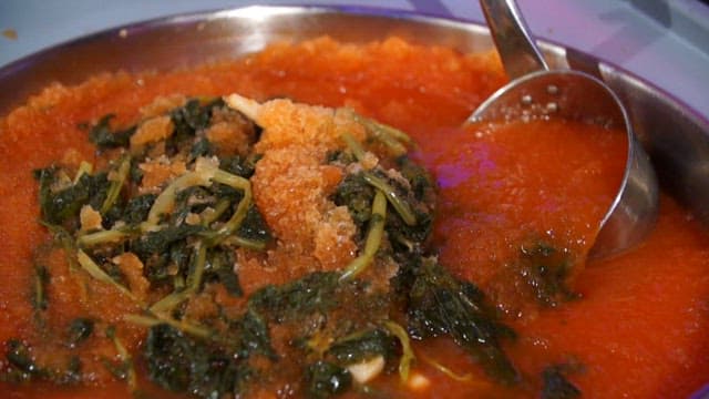 Stirring yeolmu kimchi in a big container with ladle