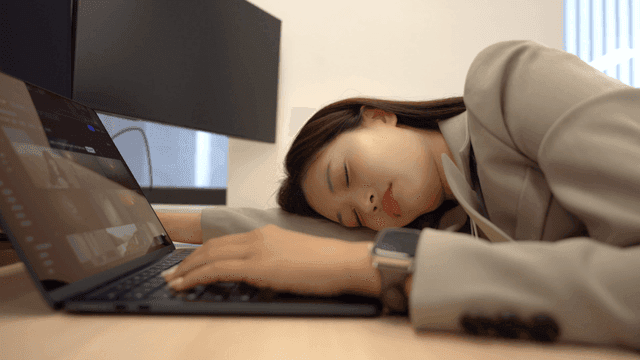Female office worker who fell asleep leaning on her side arm while working
