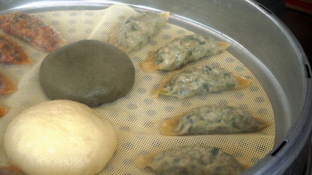 Steamed dumplings and buns being cooked at a large steamer