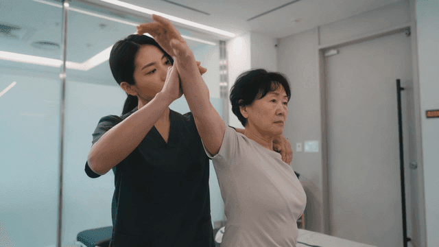 Therapist who helps elderly women with arm rehabilitation at clinic