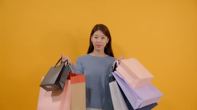 Long haired woman carrying many shopping bags and looking surprised and happy