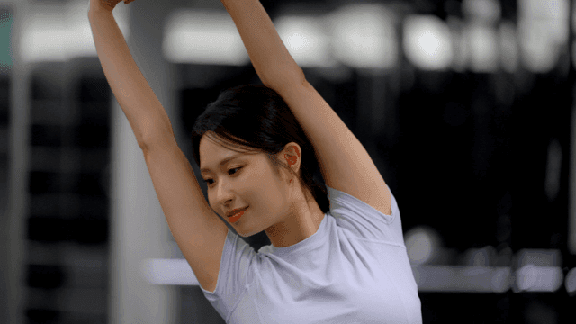 Stretching arm extended by young woman in gym
