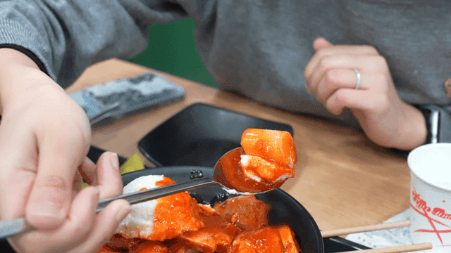 Spoonful of spicy tteokbokki topped with potato salad