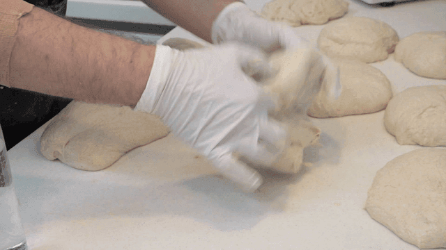 Kneading portioned dough on countertop by baker