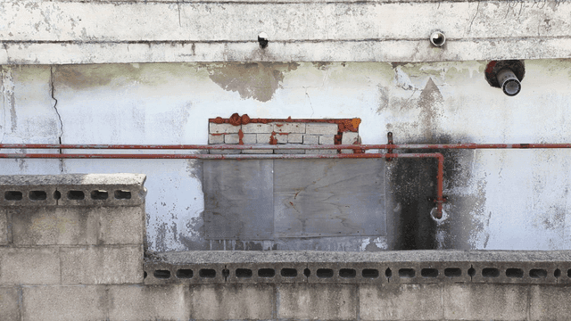 파이프와 균열이 있는 오래된 건물 벽