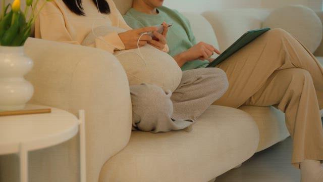 Two people using digital devices on a sofa in cozy living room