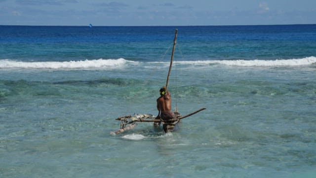 Man sailing a small boat on the clear ocean water