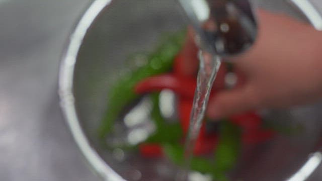 싱크대에서 흐르는 물로 고추를 씻는 사람