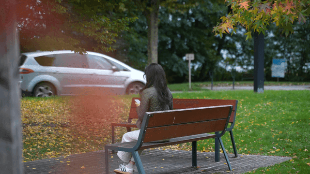 A woman sitting on a park bench with a phone