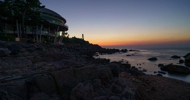 등대와 바위 해안이 있는 바다의 일몰