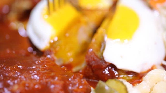 Hamburger steak topped with a fried egg is lifted with a fork