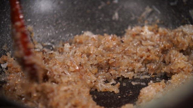 나무 주걱으로 팬에서 고기소와 당면을 볶기