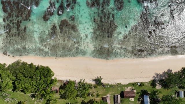 Aerial view of a beach with clear water and huts