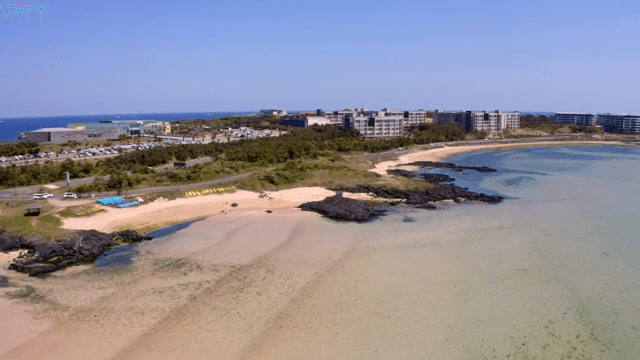 맑은 물과 먼 건물이 있는 고요한 해변