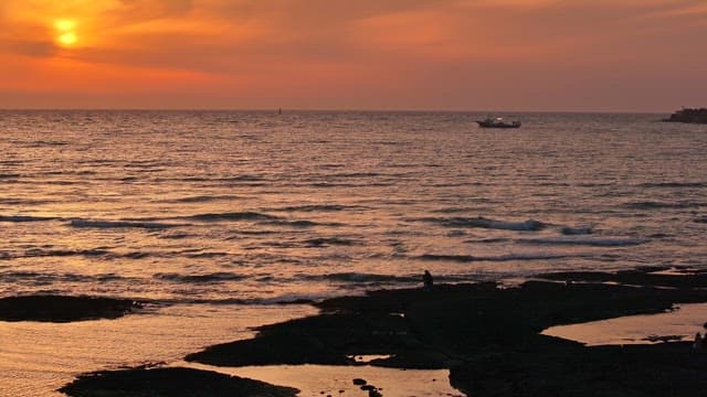 Sunset over the ocean with a distant ship