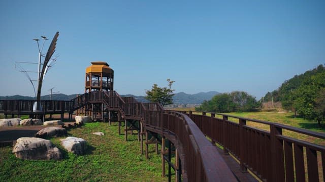 Wooden walkway in a scenic park with an observation tower on a clear day