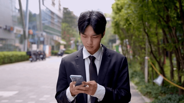 길을 걷다가 핸드폰을 확인하고 짜증난 표정의 직장인 남성