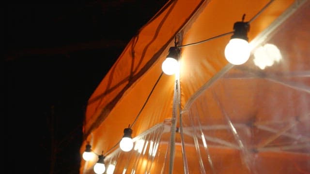 String lights on an orange tent at night.