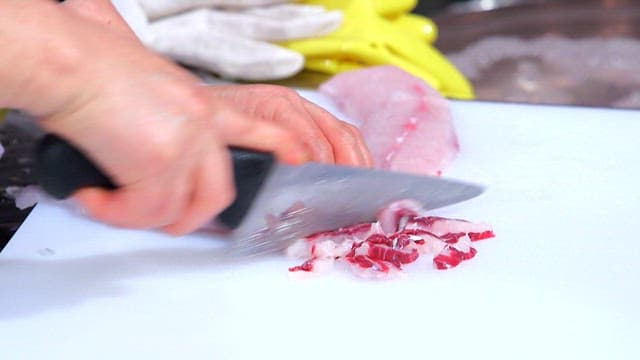 Slicing fresh gray mullet on a cutting board