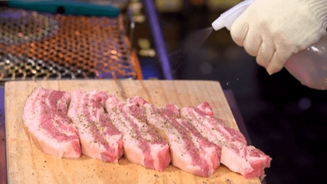 나무 도마 위에 있는 돼지고기에 소주 뿌리기