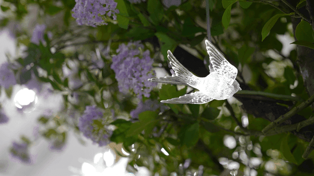 Glass bird ornament among purple flowers