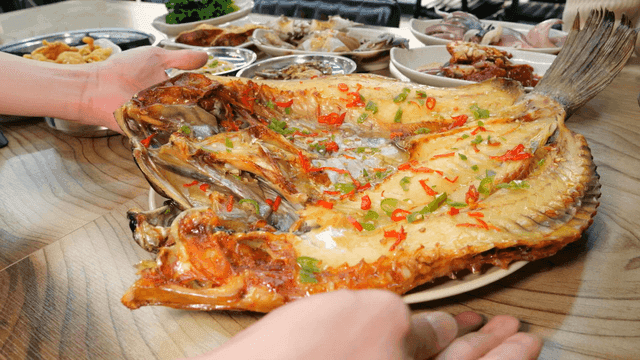 Steamed rockfish served at table with side dishes