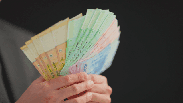 Hands holding Korean banknotes