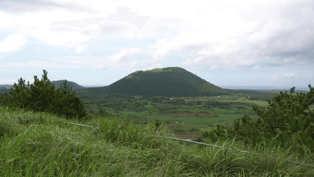 구름 낀 하늘 아래 푸른 오름